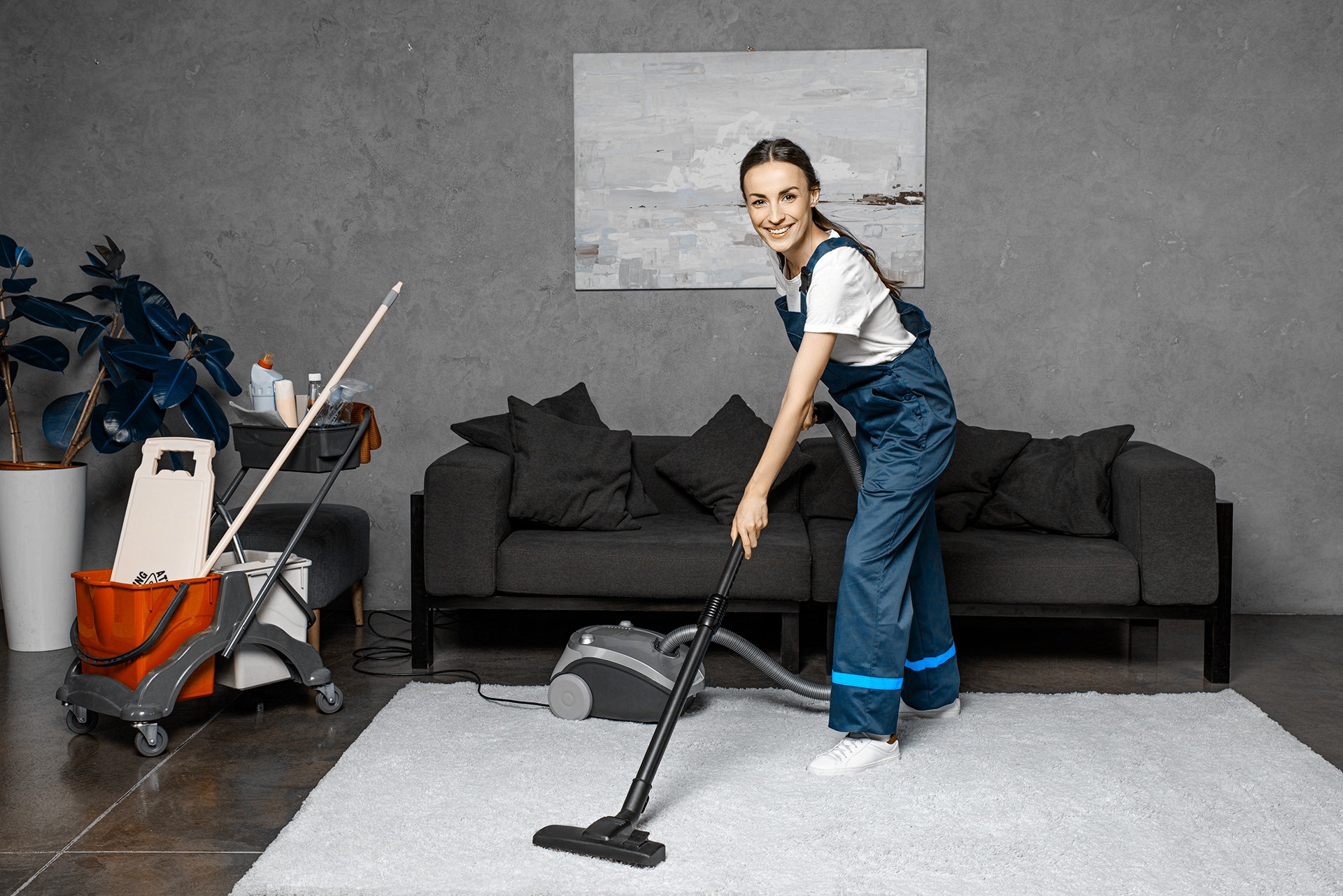 happy young female cleaning company worker using vacuum cleaner
