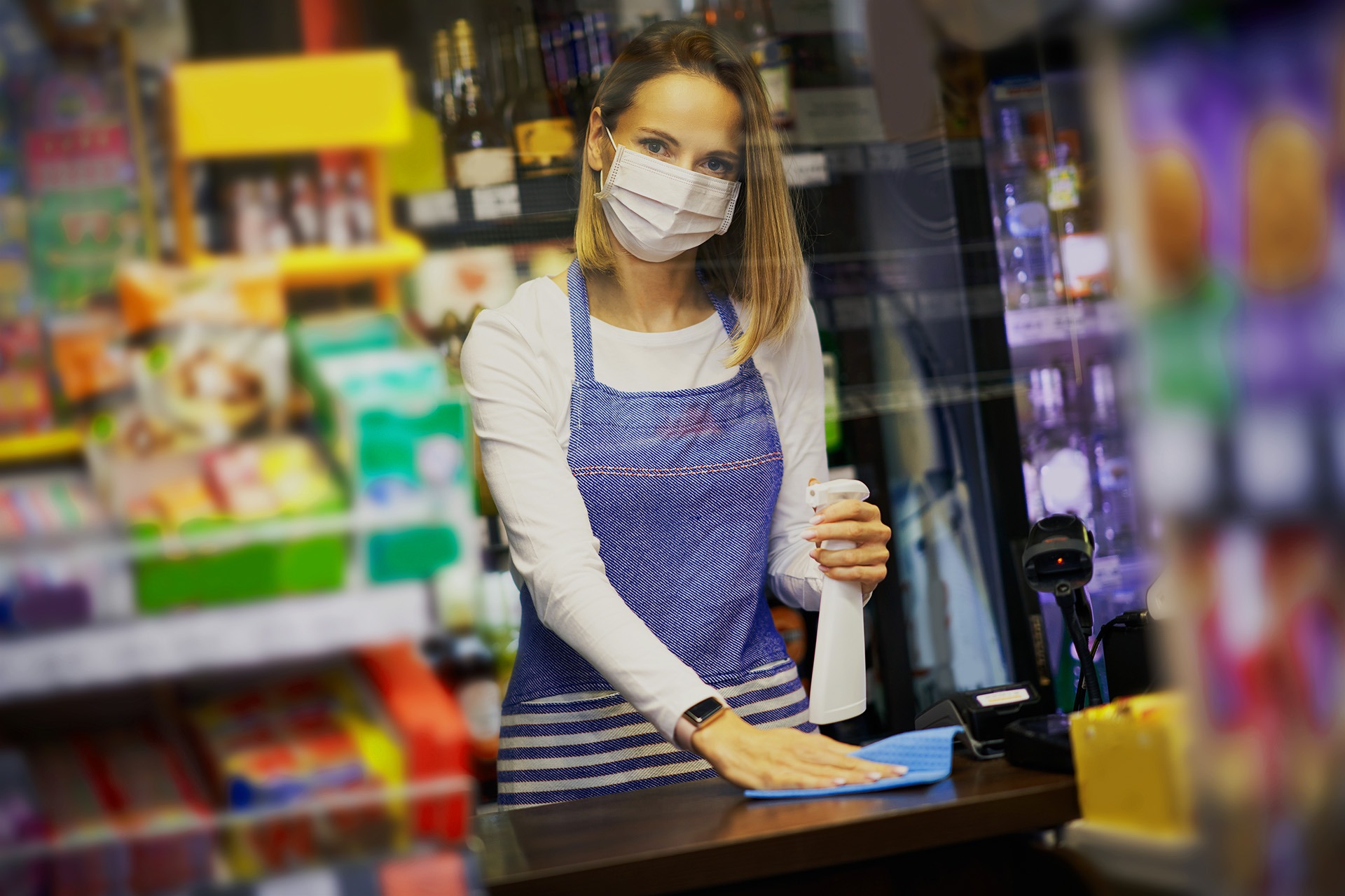 Shop assistant disinfecting surfaces in grocery store