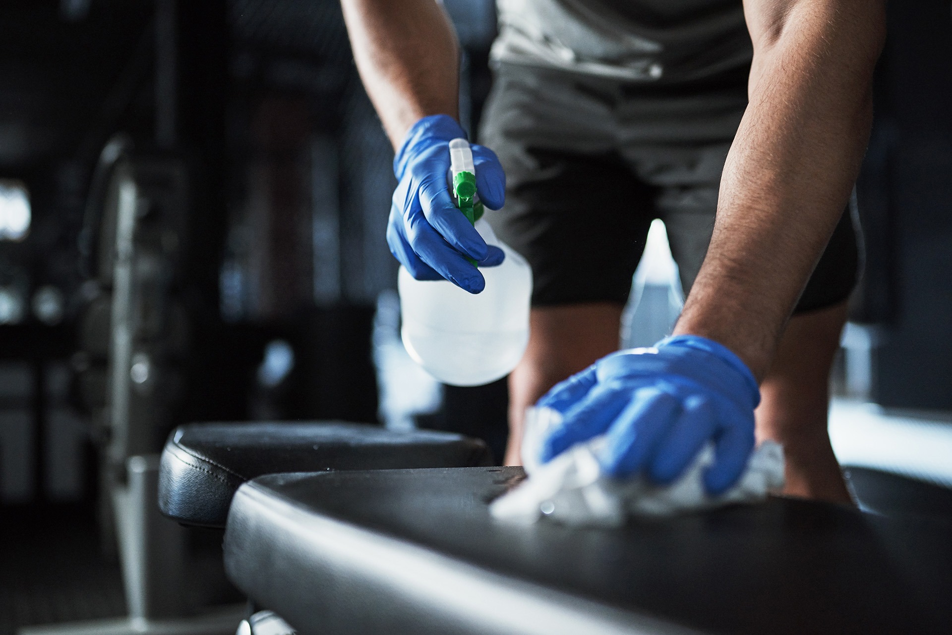 Cropped shot of an unrecognisable man disinfecting the surfaces in a gym.